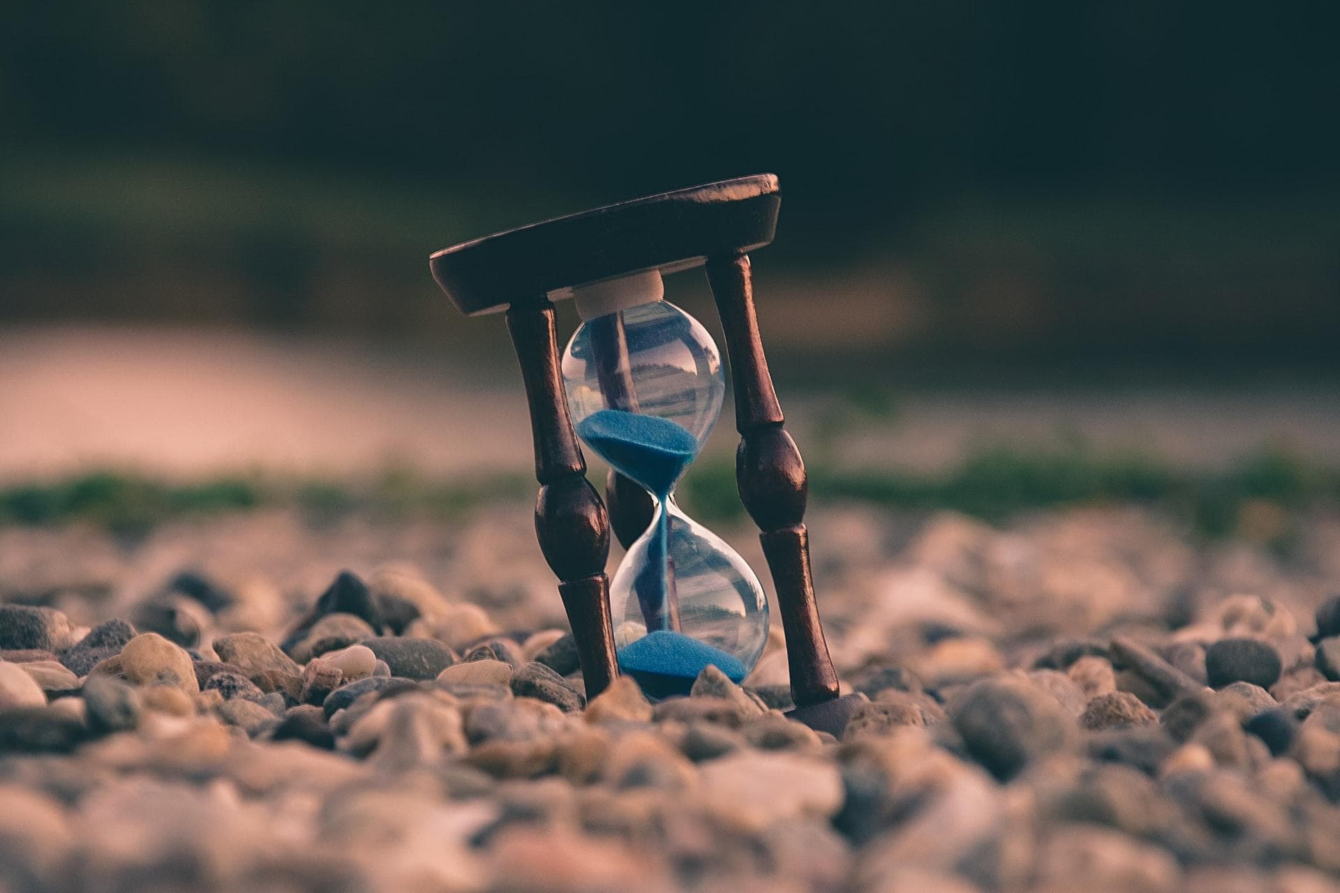 Old hourglass standing on rocky ground.