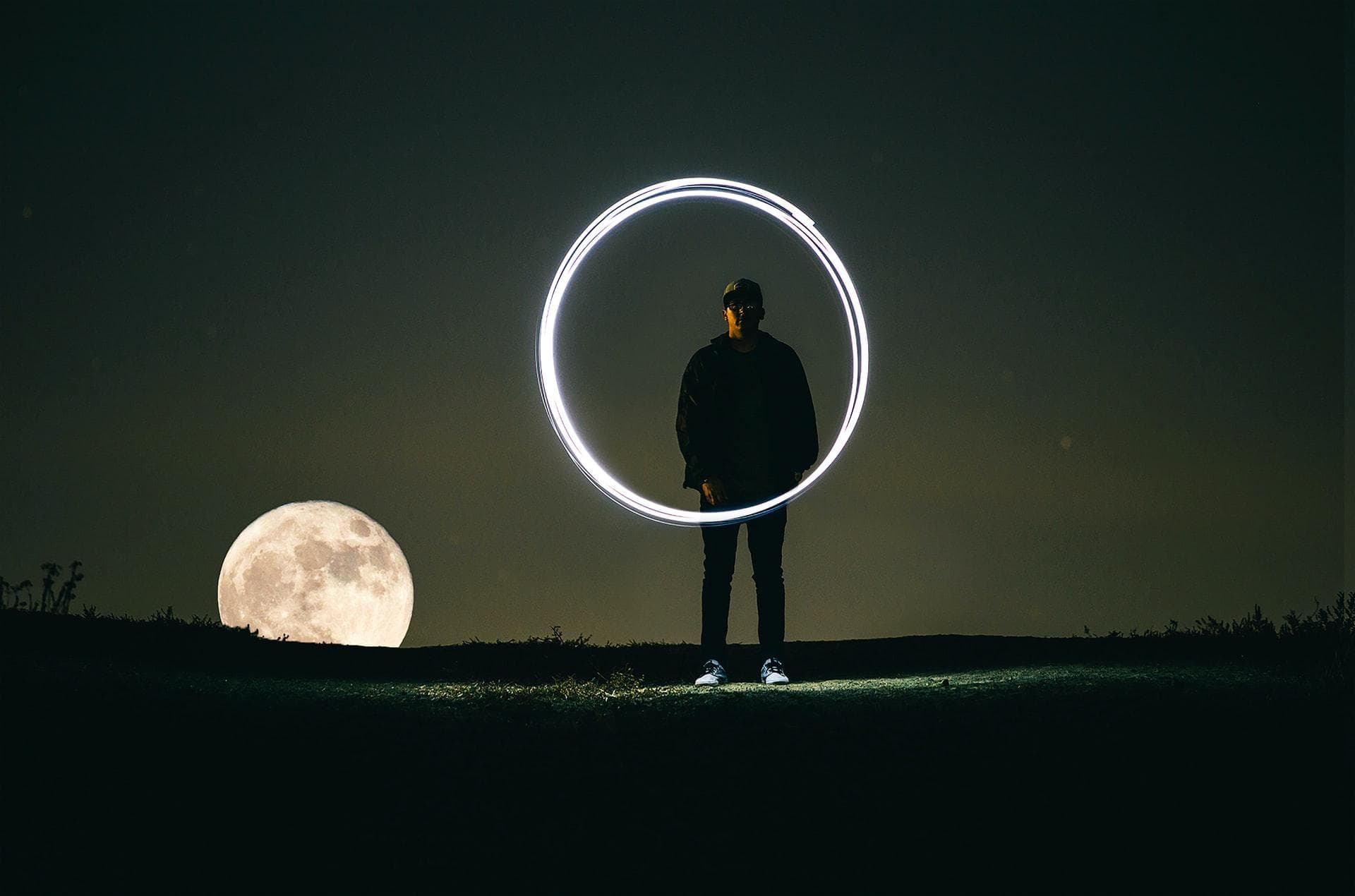 Man in the dark, painting a circle with light and long camera exposure
