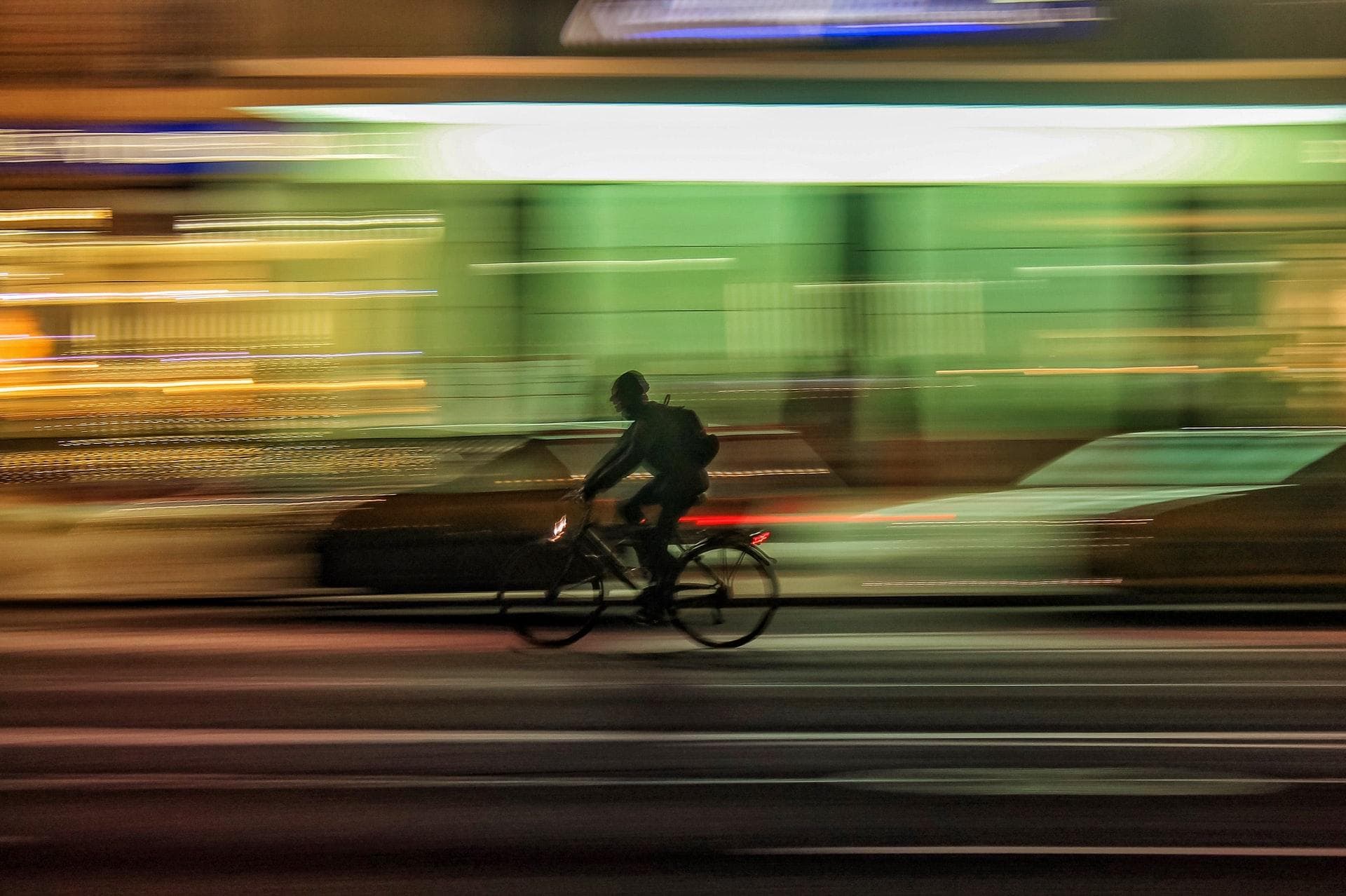 A fast biker. Background is city lights at night, blurred due to the high speed of biker